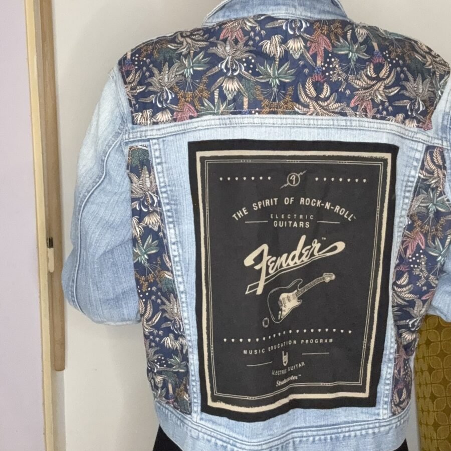 Dos de la veste en jean customisée avec patch Fender vintage et empiècements fleuris