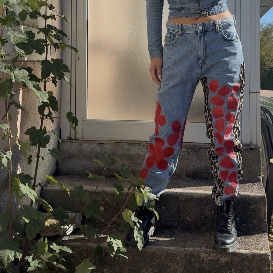 Jean vintage droit en denim délavé customisé de fleurs en vinyle rouge, vu de face