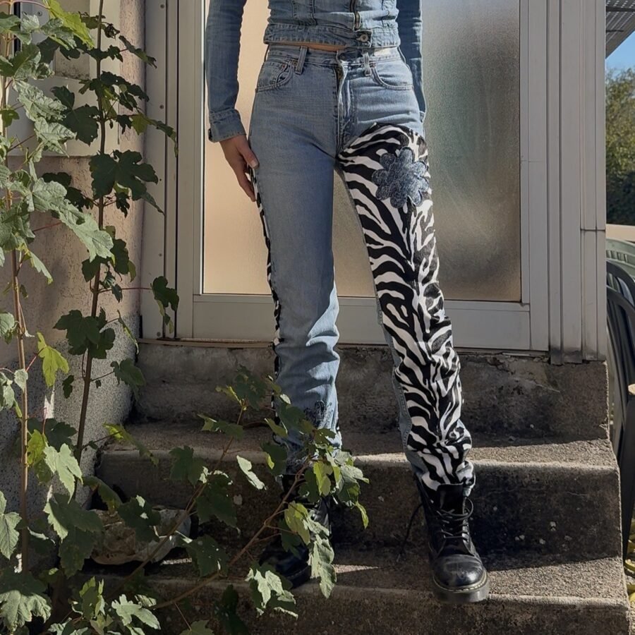 Jean 501 Levi's customisé vue de face, une jambe en imprimé zèbre avec fleur en tissu appliquée sur la hanche